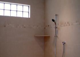 Custom walk in shower with center above head Rain shower, side wall shower heads, custom tile, and glass block window. 